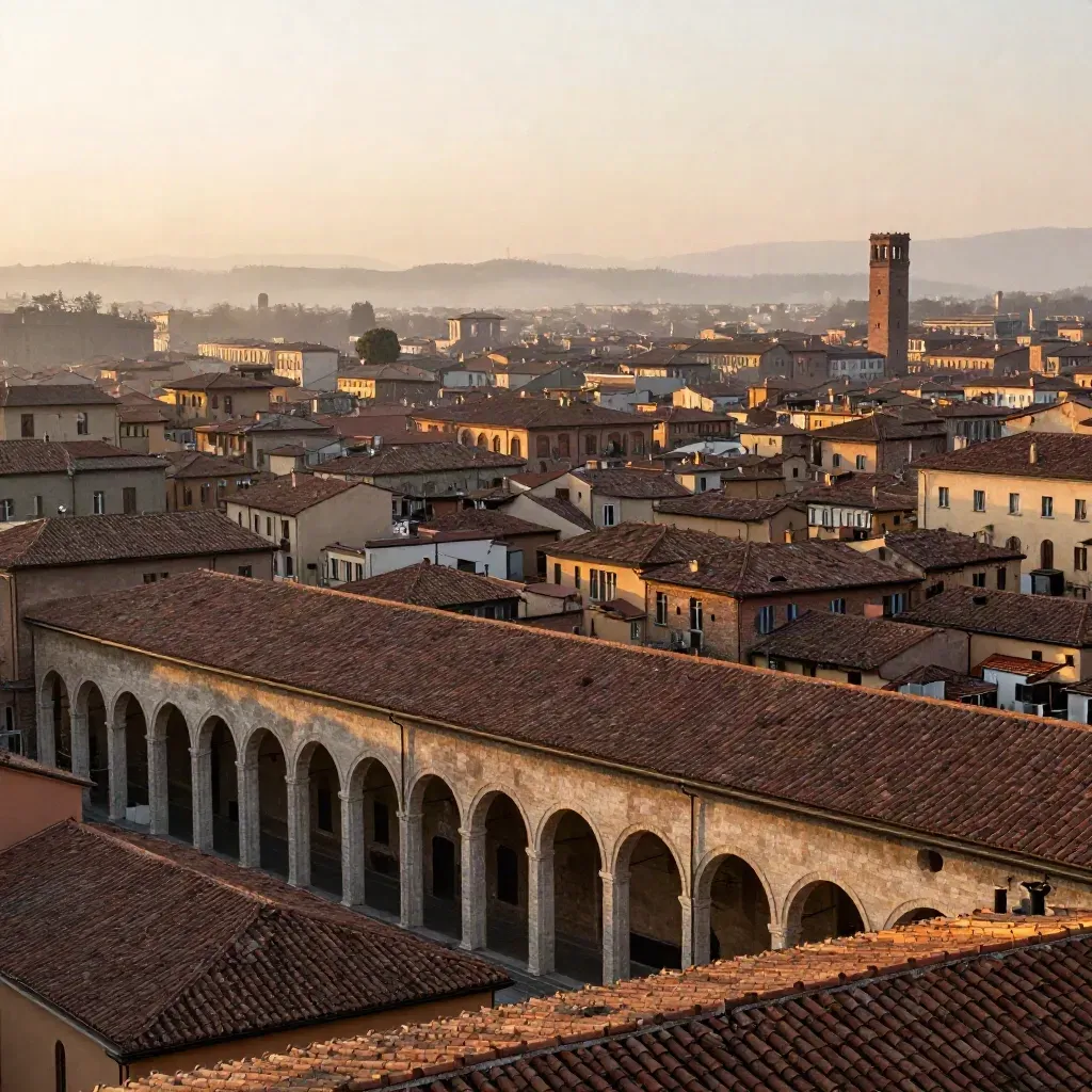 Panorama di Bologna al tramonto, tetti terracotta e portici avvolti nella foschia.